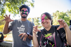 Two event workers pose like zombies with neon zombie face makeup on.