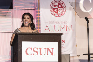 Felicia Conlan stands at a podium smiling.
