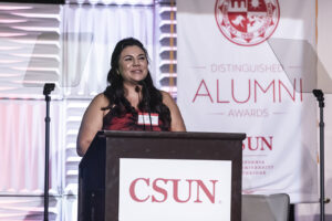 Sandra Illescas stands at the podium, smiling
