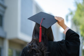 A student on graduation day holding their cap.