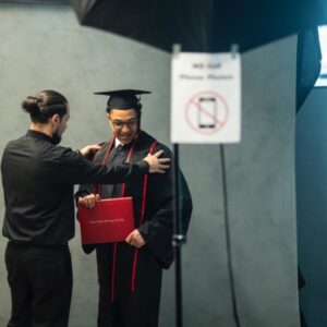 Graduation student gets positioned for a picture in his graduation cap and gown.