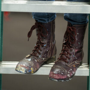 Close-up of artist's paint stained boots on stepladder.