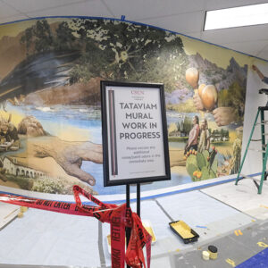 Sign in front of mural says "Work in Progress"