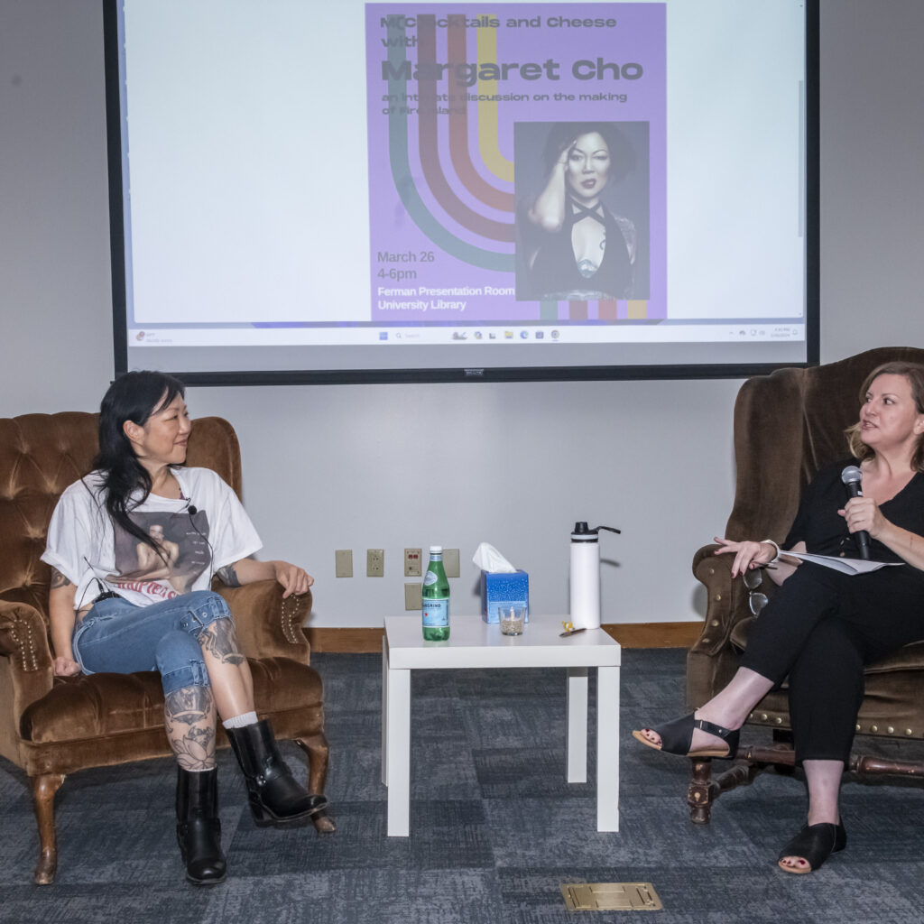 Actress Margaret Cho and Heidi Schumacher, CSUN lecturer sit in chairs facing the audience with a large screen behind them.