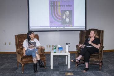 Actress Margaret Cho and Heidi Schumacher, CSUN lecturer sit in chairs facing the audience with a large screen behind them.