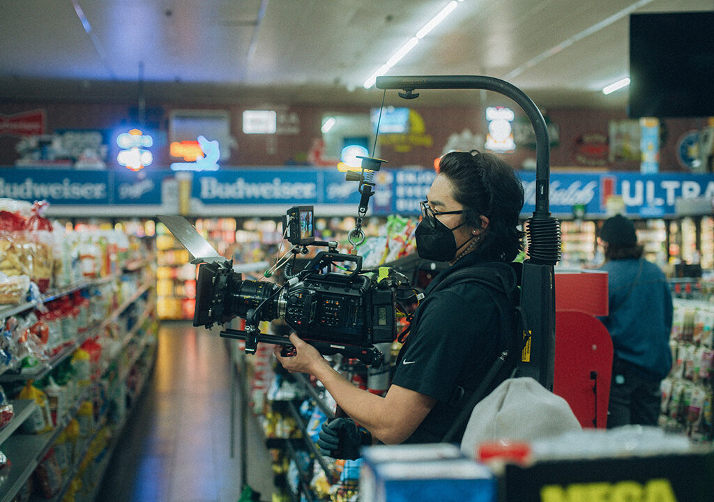 Student cameraman holding a camera and filming in a grocery store.