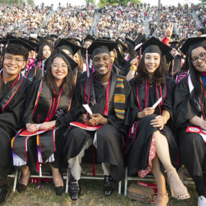 A group of students, all in cap and gown, seated and smiling at the camera.
