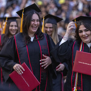 Two students laugh while holding their degrees in line at CSUN's 2024 commencement.