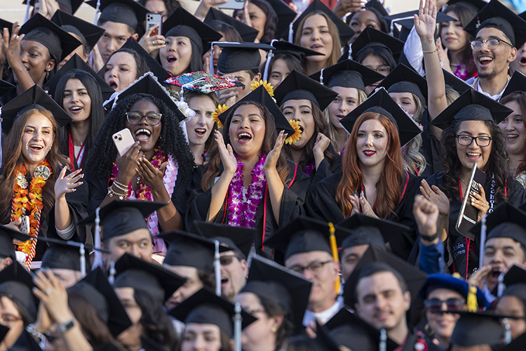 The frame is full of cheering graduates in caps and gowns at a 2024 CSUN commencement ceremony.