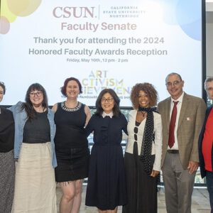 Faculty officers and committee chairs pose together in front of a screen.