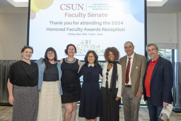 Faculty officers and committee chairs pose together in front of a screen.