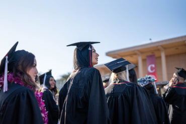A female student in cap and gown in line for commencement.