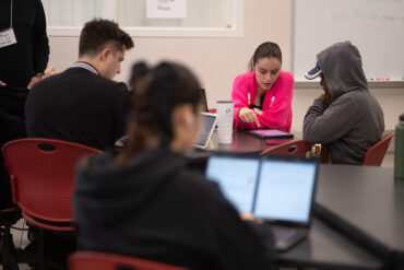 CSUN math students sit at a table and study on a tablet in a tutoring center.