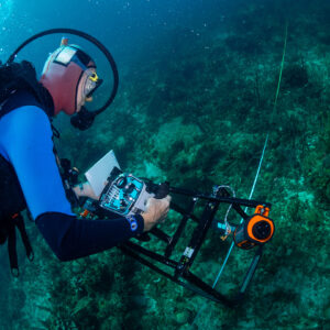 Man in scuba gear taking underwater pictures of a coral reef.
