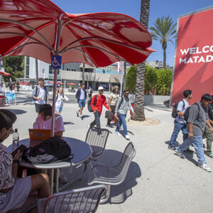 Students sit at tables under red umbrellas in the University Student Union