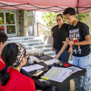 Jose Garcia stands in front of a table with his Mom standing behind him.