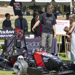 A student from CSUN's Matador Motorsports club shows off the club's hand built track car.