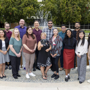 The Resource Management University Advancement department, Jolene Koester Team award winner pose for a group photo with their award, in front of there CSUN fountain.