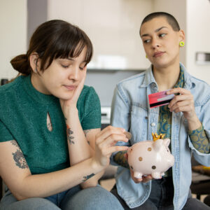 Two girls are saving money in a piggy bank