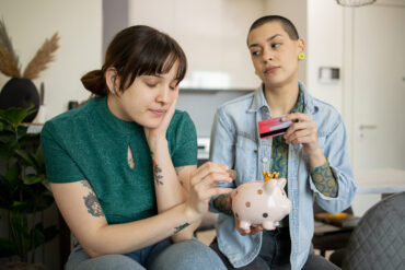 Two girls are saving money in a piggy bank