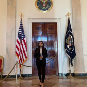 CSUN alumna Monica Barragan stands outside the door of the White House Blue Room.