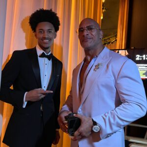 Rutledge poses backstage with actor Dwayne "The Rock" Johnson, pointing to him on his left.