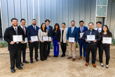 A group of 10 doctorate physical therapy students stand outside in front of a grey wall, holding framed certificates, signifying their scholarship awards. In between them is Joni Campanella, daughter of Roy and Roxie Campanella, and Chaitali Gala Mehta, LA Dodgers Foundation Chief Operating Officer.