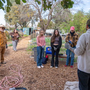 Volunteers stand in the CSUN G.A.R.D.E.N. and listen to instructions.