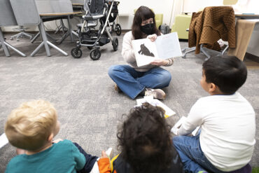 Children sit and listen to a story at Story Time in the University Library.