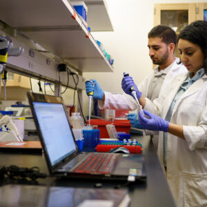 Two biology students work with lab equipment.