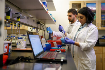 Two biology students work with lab equipment.