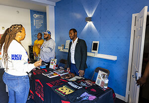 Ryan Mason stands behind a table talking with a member of the congregation.