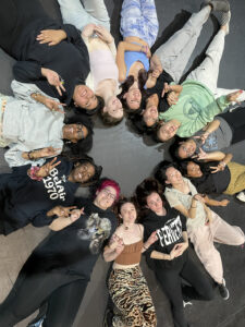 Jade C. Huell and her students laying on stage in a circle.