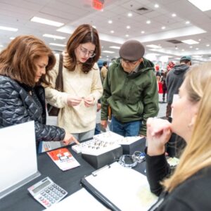Three people looking at information on a paper at a table with the person sitting at the table explaining the information to them.
