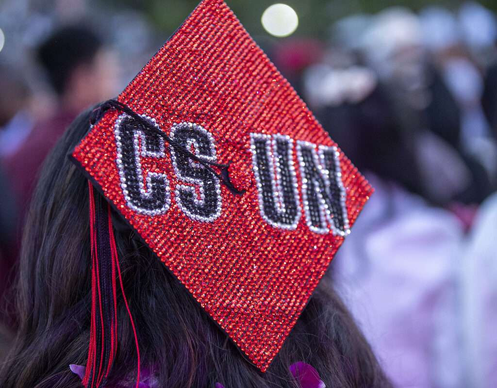A mortarboard bedazzled with "CSUN" on a sparkly red background.