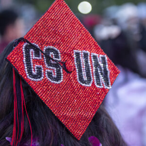 A mortarboard bedazzled with "CSUN" on a sparkly red background.