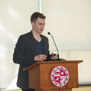 Steven Van Alen stands at podium with microphone.