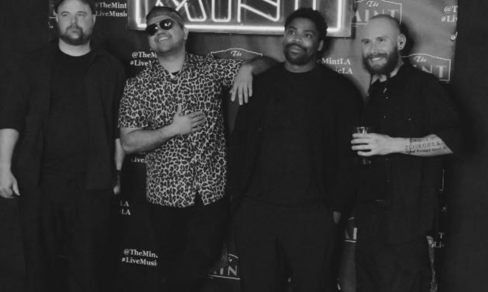 Black and white photo of all four members of the band, CANO, posting in front of a promotional backdrop