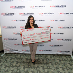 Laci Sanchez poses holding a large check.