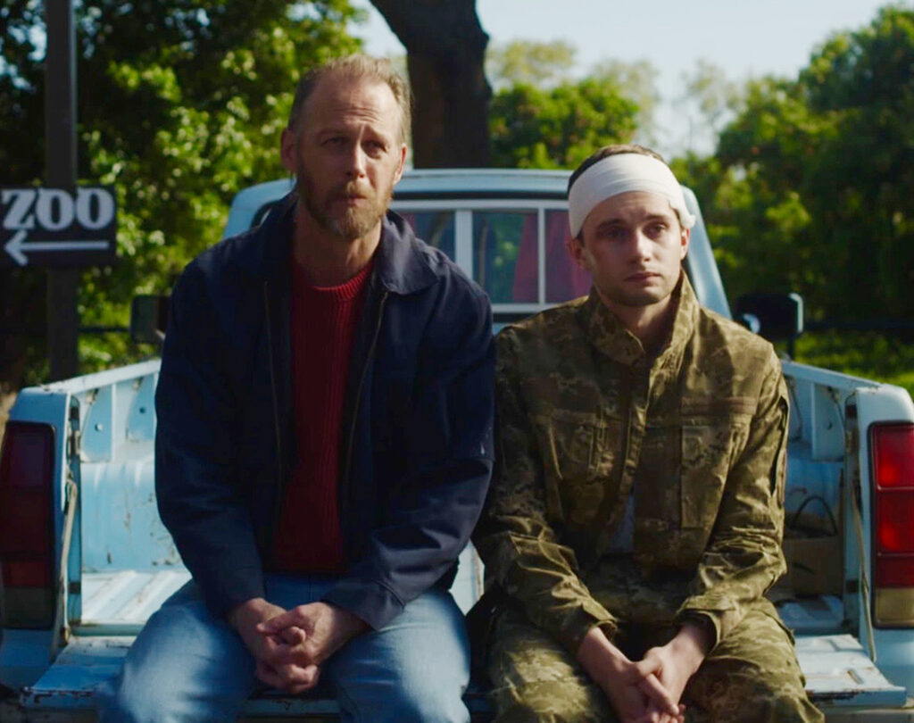 A man and his son sitting on the back of the truck.