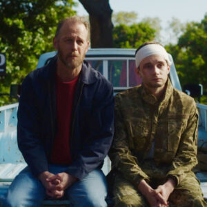 A man and his son sitting on the back of the truck.