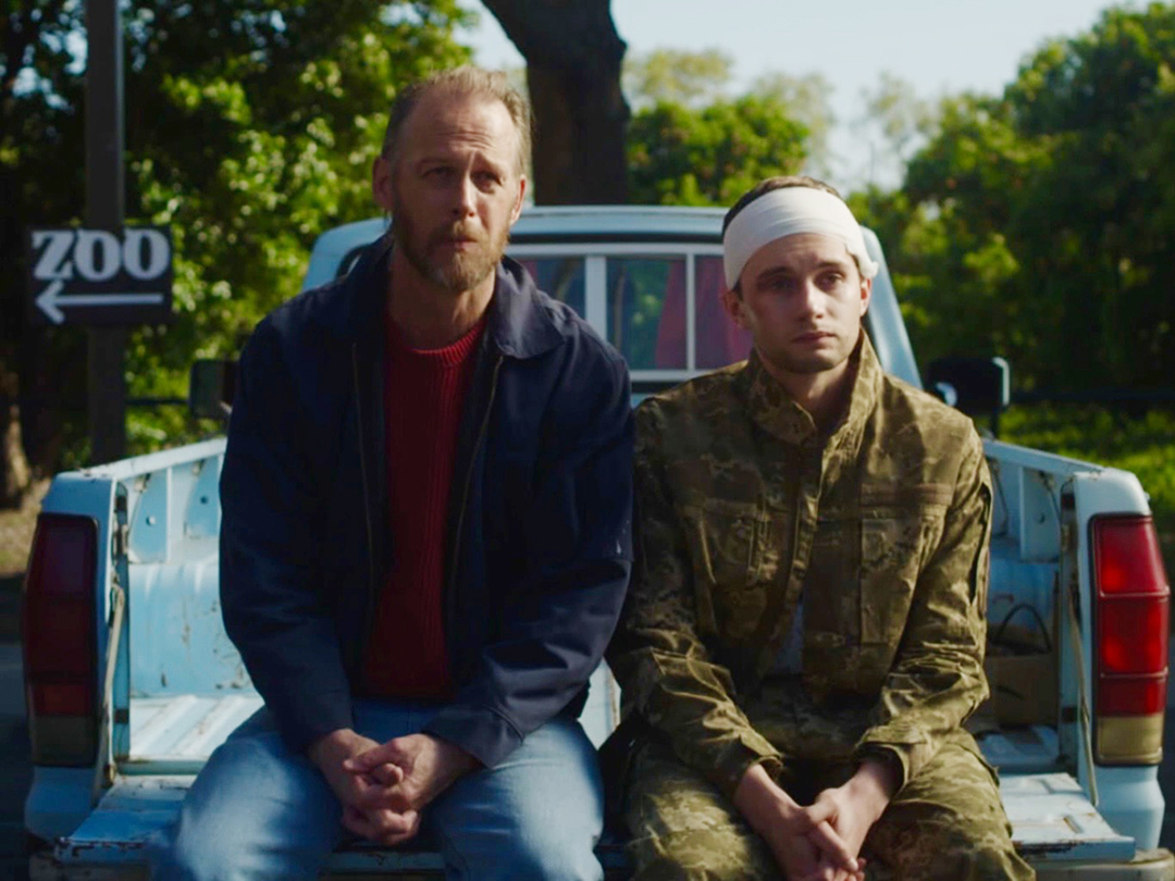 A man and his son sitting on the back of the truck.