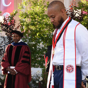 Grad student Jon Crain stands on stage with Dean Yan Searcy.