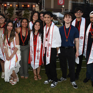 A group of graduates wearing sashes pose for the camera.