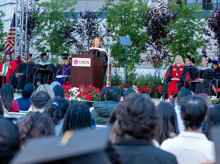 Lisa Jackson stands at podium addressing the graduates.