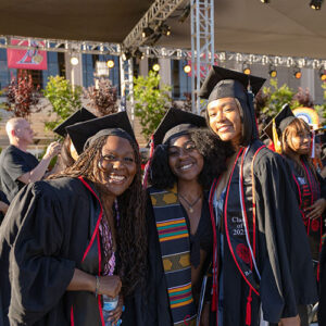 Three women in caps and gowns pose for the camera.