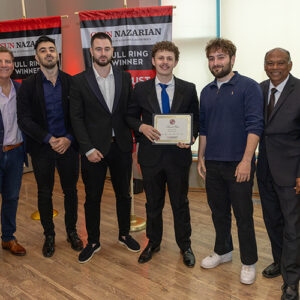 The winners of second place stand on stage with their certificate.