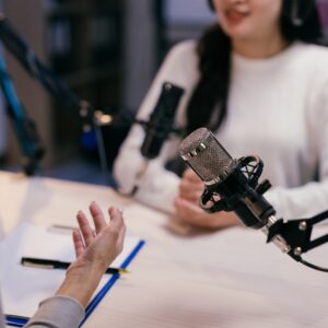 Two young female podcasters are recording a podcast episode, engaging in a lively discussion and sharing their insights with their audience.