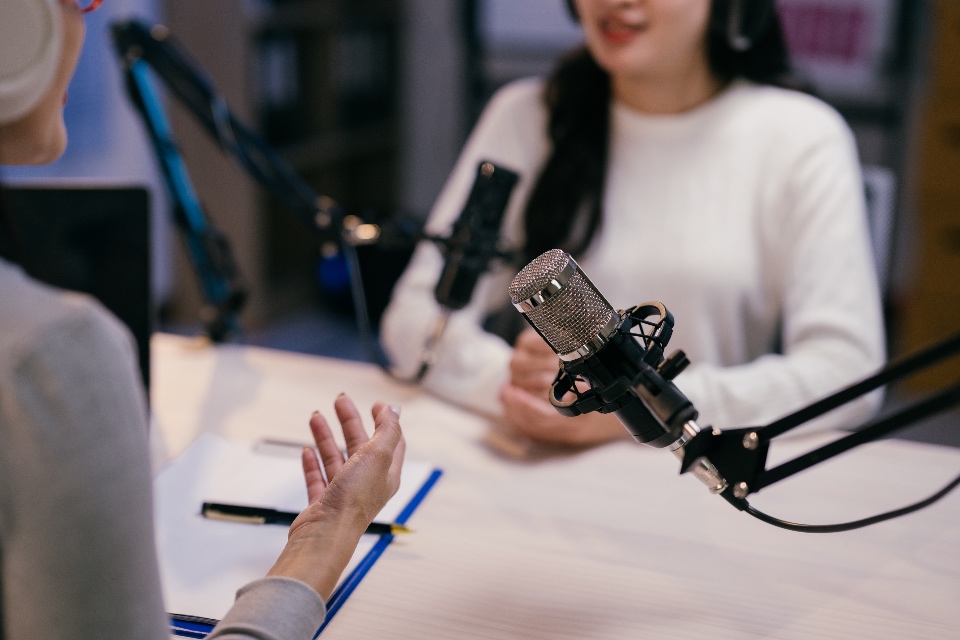 Two young female podcasters are recording a podcast episode, engaging in a lively discussion and sharing their insights with their audience.