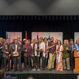 Veteran graduates stand on stage and pose for a group photo.